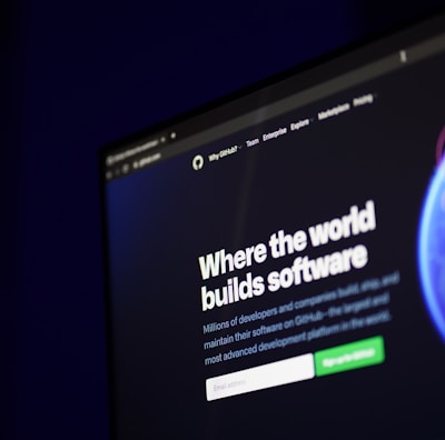 A computer screen displays a website with the text 'Where the world builds software' prominently featured. Below the text, there are fields for users to input their email address, along with additional descriptions about the platform and its capabilities. The website has a dark background with bright text, indicating a professional tech-based service.